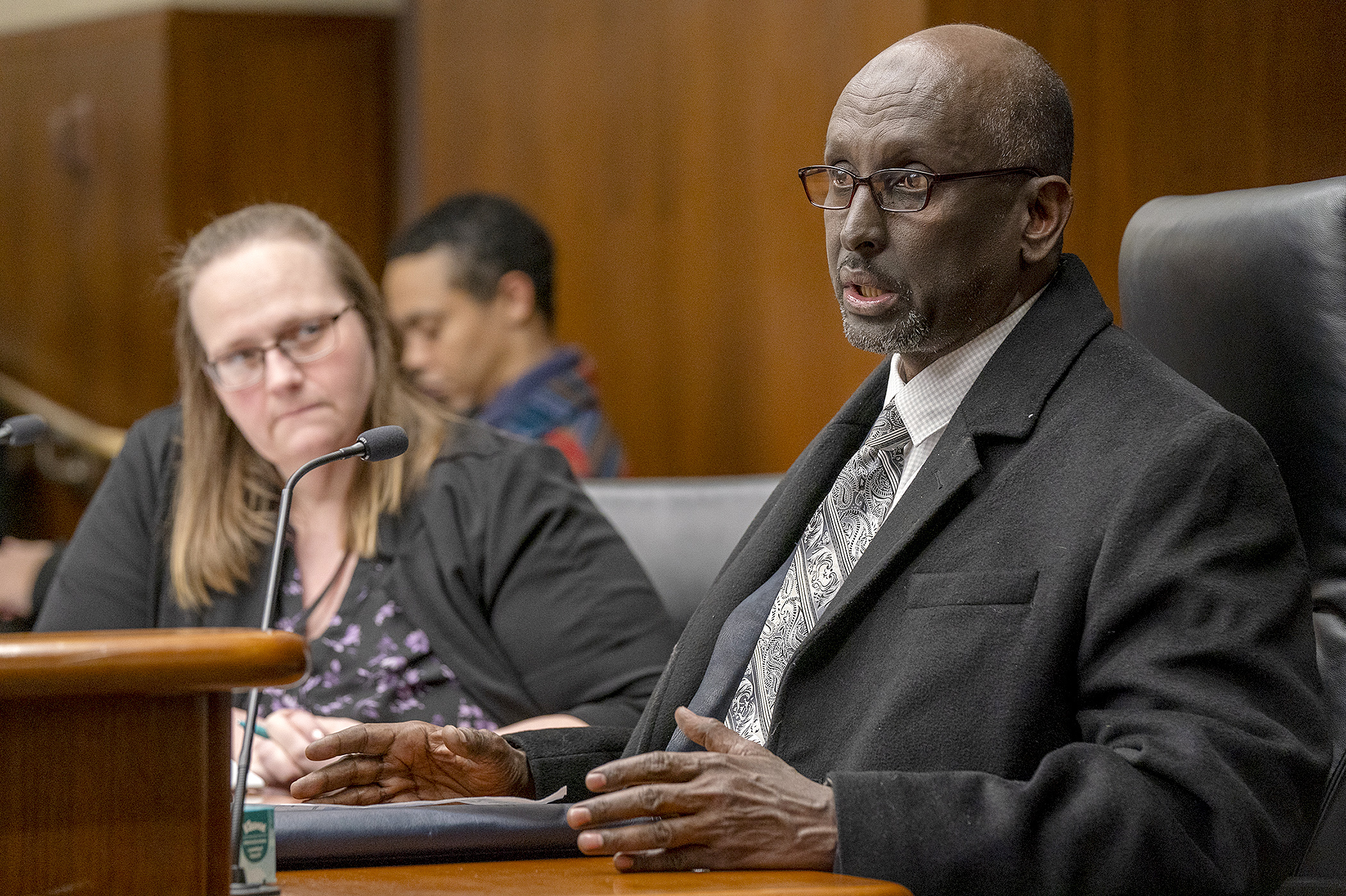 Omar Nur, executive director of the Somali American Social Service Association, testifies before the House Human Services Policy Committee regarding HF3098. The bill is sponsored by Rep. Kim Hicks, left. (Photo by Michele Jokinen)